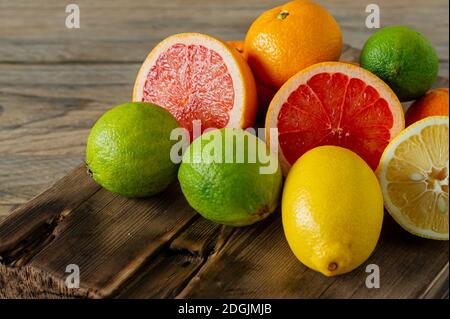 Moitiés d'agrumes frais sur fond en bois. Orange, pamplemousse, lime, citron, rondelles coupées à la mandarine Banque D'Images