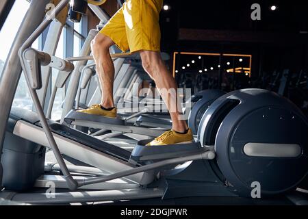 Athlète masculin utilisant l'entraîneur elliptique à la salle de gym Banque D'Images