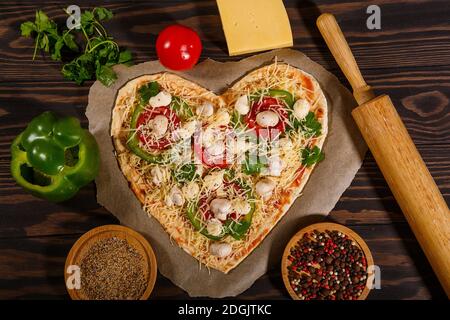Pizza avant cuisson, légumes et épices sur fond de bois sombre Banque D'Images