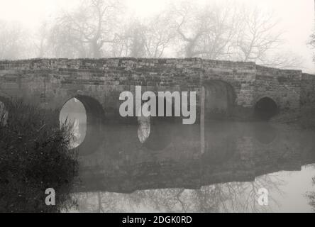 pont en pierre dans le brouillard avec réflexion dans l'eau Banque D'Images