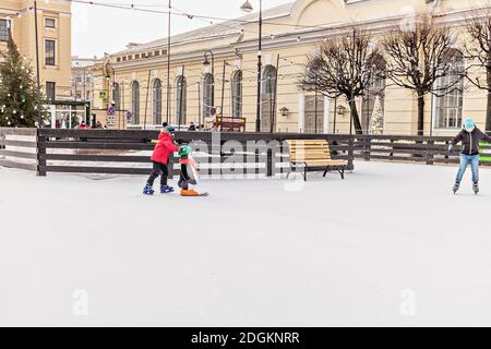 Les enfants patinent sur la patinoire de la place de la ville. Vacances de Noël. Banque D'Images