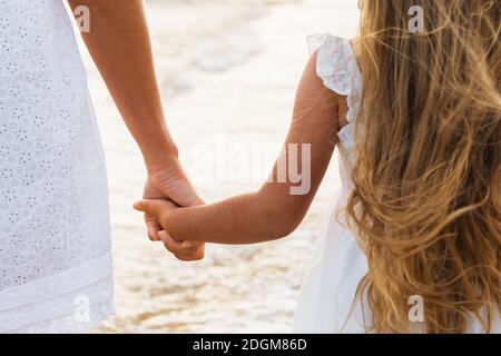 Maman et fille tiennent les mains, gros plan. Un concept sur la relation entre les parents et les enfants. Banque D'Images