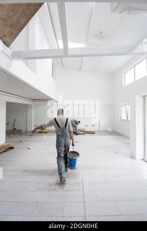 Ouvriers installant les carreaux de céramique à effet de bois sur le sol Banque D'Images