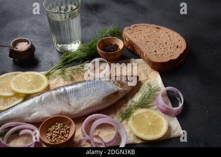 Poisson de hareng sur bois avec poivre, herbes, oignon rouge et citron sur fond noir. Vue de dessus avec espace de copie avec tranches de pommes de terre et le seigle bre Banque D'Images