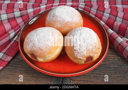 Beignets dans une assiette rouge sur une table en bois avec une nappe Banque D'Images