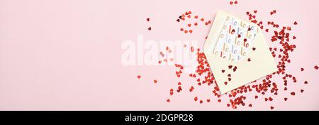 Enveloppe en papier avec carte de vœux et confettis en forme de coeur rouge sur fond rose pastel. Flat lay, vue de dessus, espace de copie. Fête des mères ou Saint-Valentin d Banque D'Images