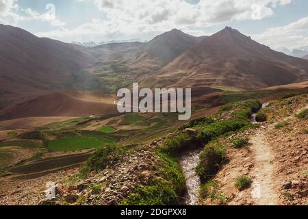 Une vue panoramique de la lumière du soleil frappant les champs verts et les montagnes dans le village himalayan de Kibber dans la vallée de Spiti. Banque D'Images