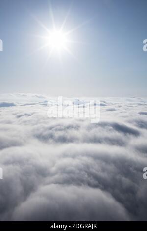 Soleil brillant dans le ciel bleu au-dessus des nuages Banque D'Images