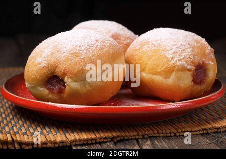 Beignets avec confiture dans une assiette rouge sur une ancienne table en bois. Mise au point sélective Banque D'Images