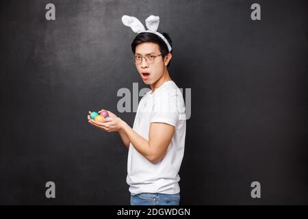 Vacances, fête et Pâques concept. Portrait de profil de sassy drôle et ludique asiatique jeune homme se tourner vers l'appareil photo dans les oreilles de lapin an Banque D'Images