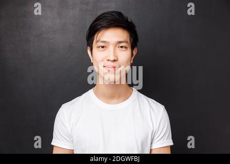 Portrait en gros plan d'un jeune homme asiatique souriant et sympathique, en t-shirt blanc, regardant l'appareil photo et le sourire, debout Banque D'Images