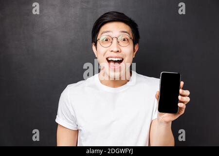 Technologie, messagerie et concept de personnes. Portrait en gros plan d'un heureux, surpris et impressionné jeune asiatique excité en blanc t Banque D'Images