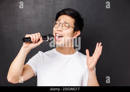 Loisirs, personnes et concept de musique. Gros plan de passionné et insouciant asiatique gars aime chanter des chansons, tenant le microphon Banque D'Images