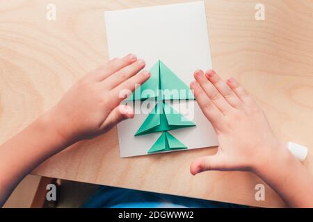 Étape 5 de la création de la carte de Noël. Collez les parties préparées de l'arbre de Noël sur la feuille de cartes. Deux cartes de Noël faites par les mains d'un adulte et d'un enfant. Banque D'Images