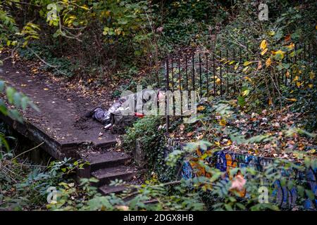 Un homme couché sur une plate-forme de chemin de fer abandonnée, vêtements rugueux, plein air, bois, automne Banque D'Images