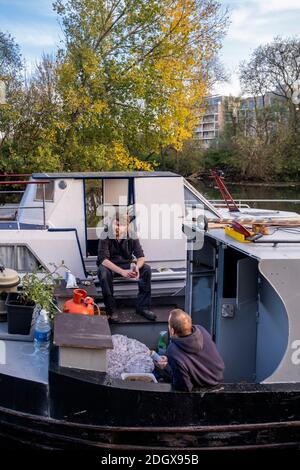 Propriétaires résidents de péniche discutant sur leur bateau de rivière, canal navigable de la vallée de Lea en automne Banque D'Images