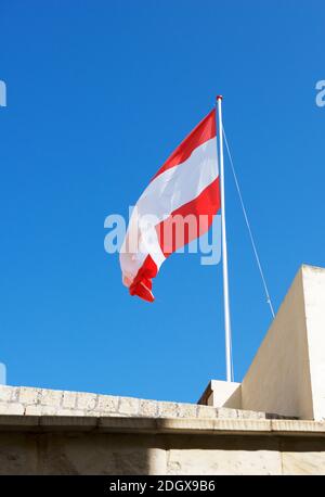 Drapeau maltais soufflant le jour ensoleillé dans le village de Zurrieq, Malte Banque D'Images