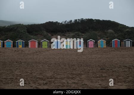 Une rangée colorée de cabanes de plage à Saunton Sands lors d'une journée sombre et surmontée, tous les jours se ferment hors saison. Banque D'Images