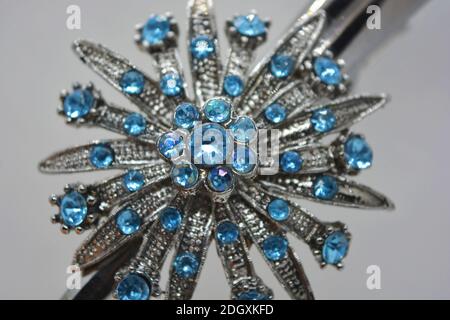 Une grande belle femelle bijoux en métal avec des pierres bleues, des gravures, une forme inhabituelle est située sur un fond blanc mat. Banque D'Images