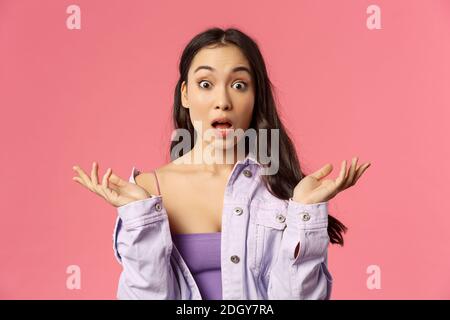 Portrait en gros plan de la jeune femme asiatique sans voix, impressionnée, écartant les mains sur le côté, le souffle et la bouche ouverte large de l'étonnement, Banque D'Images