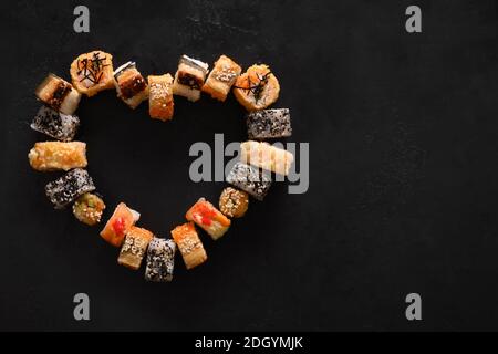 Sushi sur fond noir. Concept de la Saint-Valentin. Vue de dessus. Espace pour le texte. Style de pose à plat. Banque D'Images