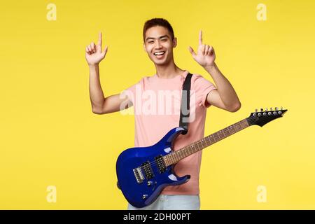 Concept de style de vie, de loisirs et de jeunesse. Joyeux et enthousiaste, un jeune homme asiatique se fait remarquer, se portant sur scène, Hol Banque D'Images