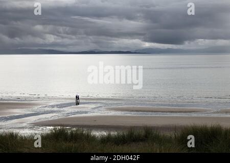 Deux personnes marchant sur une plage déserte à l'approche de nuages de pluie, Sands Bay, Gairloch, Écosse, Royaume-Uni Banque D'Images