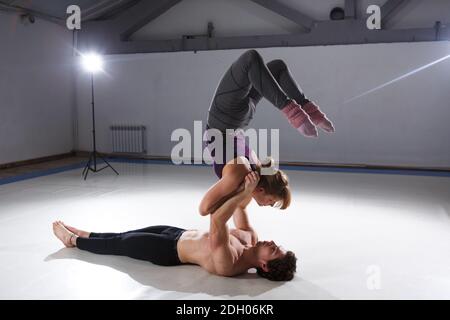 Le thème de l'Acroyoga et du Yoga pose. Acroyogis en train de pratiquer. Avec le rétroéclairage studio. La base man tient dans le statique pose un woma Banque D'Images