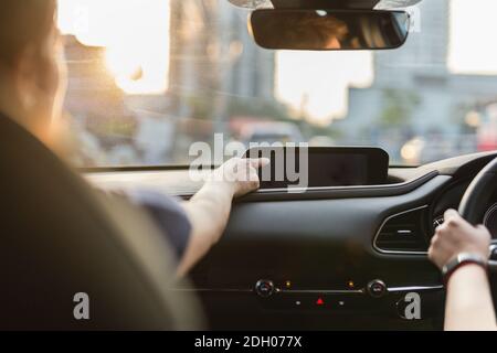 Femme main touchant l'écran dans la voiture pendant que son ami conduit. Banque D'Images