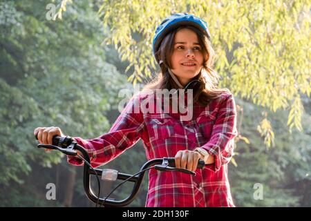 Sujet mode écologique de transport vélo. Belle jeune femme kasazy portant un casque bleu et de longs cheveux poses debout ne Banque D'Images