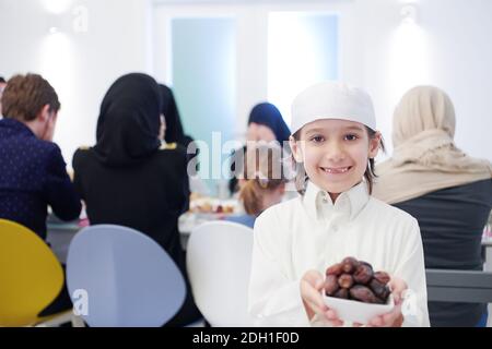 Petit garçon musulman tenant une assiette pleine de dates sucrées Banque D'Images