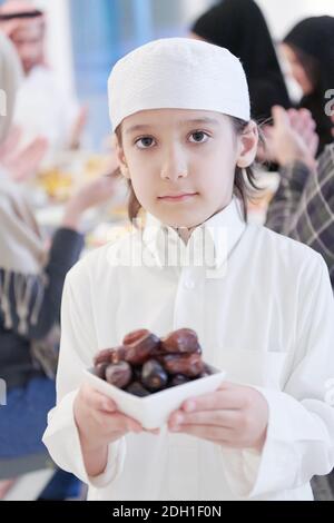 Petit garçon musulman tenant une assiette pleine de dates sucrées Banque D'Images
