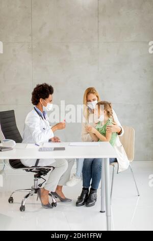 Mère avec sa petite fille à l'examen pédiatre et Avoir un test de diagnostic PCR par une femme médecin afro-américaine Banque D'Images