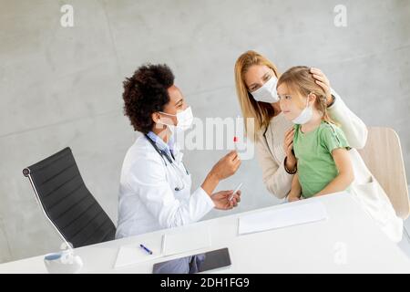 Mère avec sa petite fille à l'examen pédiatre et Avoir un test de diagnostic PCR par une femme médecin afro-américaine Banque D'Images