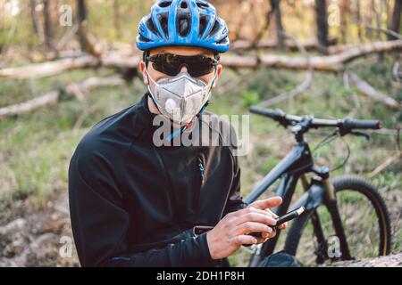 Cycliste portant un masque de pollution. Jeune homme en respirateur avec filtre pm 2.5 avec vélo dans le parc. Sports de quarantaine Covid 19. Grippe ep Banque D'Images