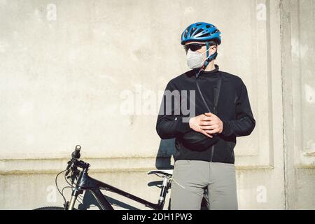 Cycliste dans le masque facial en raison du smog dans la ville. Vélo de coursier faisant une livraison. Homme portant un masque de coronavirus Covid 19. Entrée cycliste Banque D'Images