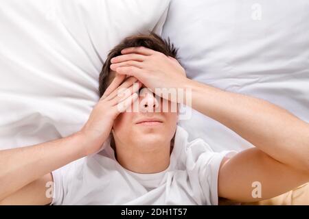 Un jeune homme ressent des maux de tête dans le lit à la maison Banque D'Images