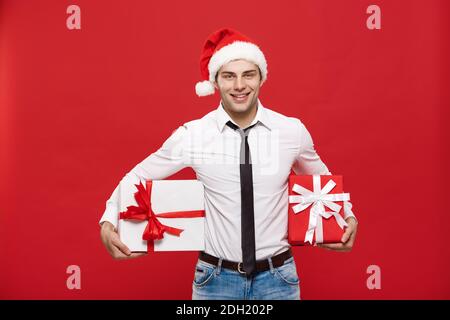 Concept de Noël - portrait heureux homme d'affaires de noël de Noël passionnant avec son cadeau sur fond rouge. Banque D'Images