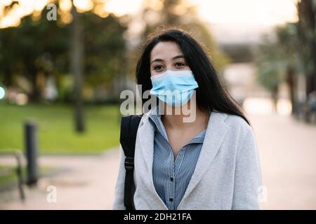 Portrait d'une heureuse femme exécutive ou d'un étudiant marchant dans la rue en portant un masque facial en raison de la pandémie du coronavirus 2020 Covid-19 à Saint-Valent Banque D'Images