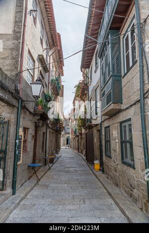 Guimaraes / Portugal - 12 09 2020 : vue sur une rue ancienne et étroite avec des bâtiments classiques sur le centre ville de Guimaraes, homme marchant et magasins Banque D'Images