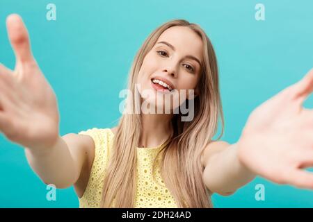 Close-up portrait of attractive young woman stretching her arms, veut vous embrasser. Isolé sur fond bleu. Banque D'Images