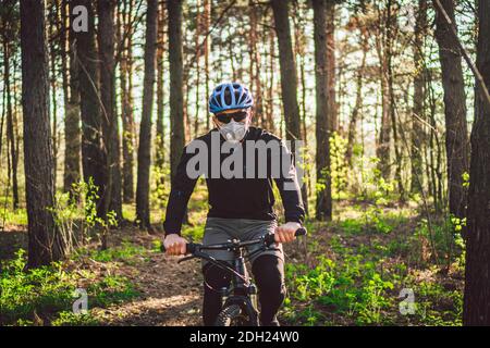 Cycliste portant un masque de pollution. Jeune homme en respirateur avec filtre pm 2.5 avec promenade à vélo dans le parc. Covid 19 quarantaine Sport. Banque D'Images