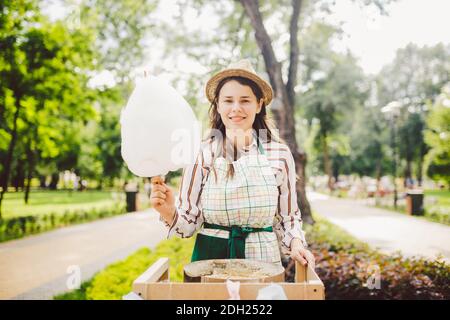 Photo thème petits affaires de cuisine bonbons. Une jeune femme caucasienne avec un négociant de tablier dans le chapeau que le propriétaire du point de vente fait Banque D'Images