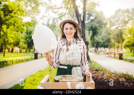 Photo thème petits affaires de cuisine bonbons. Une jeune femme caucasienne avec un négociant de tablier dans le chapeau que le propriétaire du point de vente fait Banque D'Images