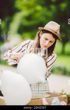 Photo thème petits affaires de cuisine bonbons. Une jeune femme caucasienne avec un négociant de tablier dans le chapeau que le propriétaire du point de vente fait Banque D'Images