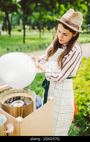 Photo thème petits affaires de cuisine bonbons. Une jeune femme caucasienne avec un négociant de tablier dans le chapeau que le propriétaire du point de vente fait Banque D'Images