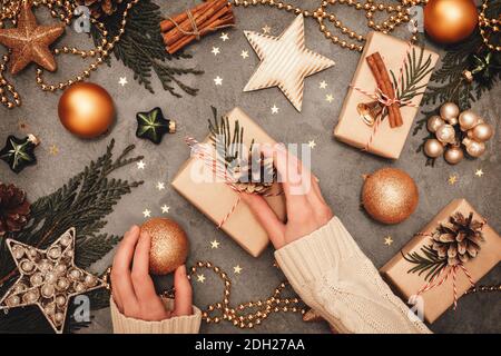 Carte traditionnelle rustique de Noël et du nouvel an. Branches de cèdre décorées avec soin sur un panneau de béton gris. Boîtes-cadeaux artisanales, balles dorées, Banque D'Images