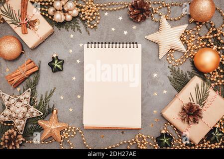 Bloc-notes avec décorations de vacances dans des couleurs vertes et dorées sur fond de béton gris, copyspace. Concept de plan de Noël et de nouvel an. L'ARC Banque D'Images