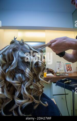 Coiffeur curling les cheveux d'une femme blonde Banque D'Images