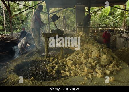 L'ouvrier de l'usine charge le système de filtration avec du soufre fondu dans des fumées toxiques toxiques toxiques toxiques toxiques toxiques toxiques toxiques à l'usine de soufre dans le village de Tamansari à l'est de Java, en Indonésie. L'usine située dans la jungle à côté du village traite de 9 à 12 tonnes de soufre par jour provenant des mines de soufre à proximité dans le cratère du volcan actif de Kawah Ijen. Le soufre est fondu à l'usine, puis filtré et chargé dans des sacs. Les travailleurs travaillent ici dans des fumées toxiques toxiques toxiques toxiques toxiques toxiques. On croit que le travail à l'usine est encore plus dangereux que celui des mines de soufre. Banque D'Images